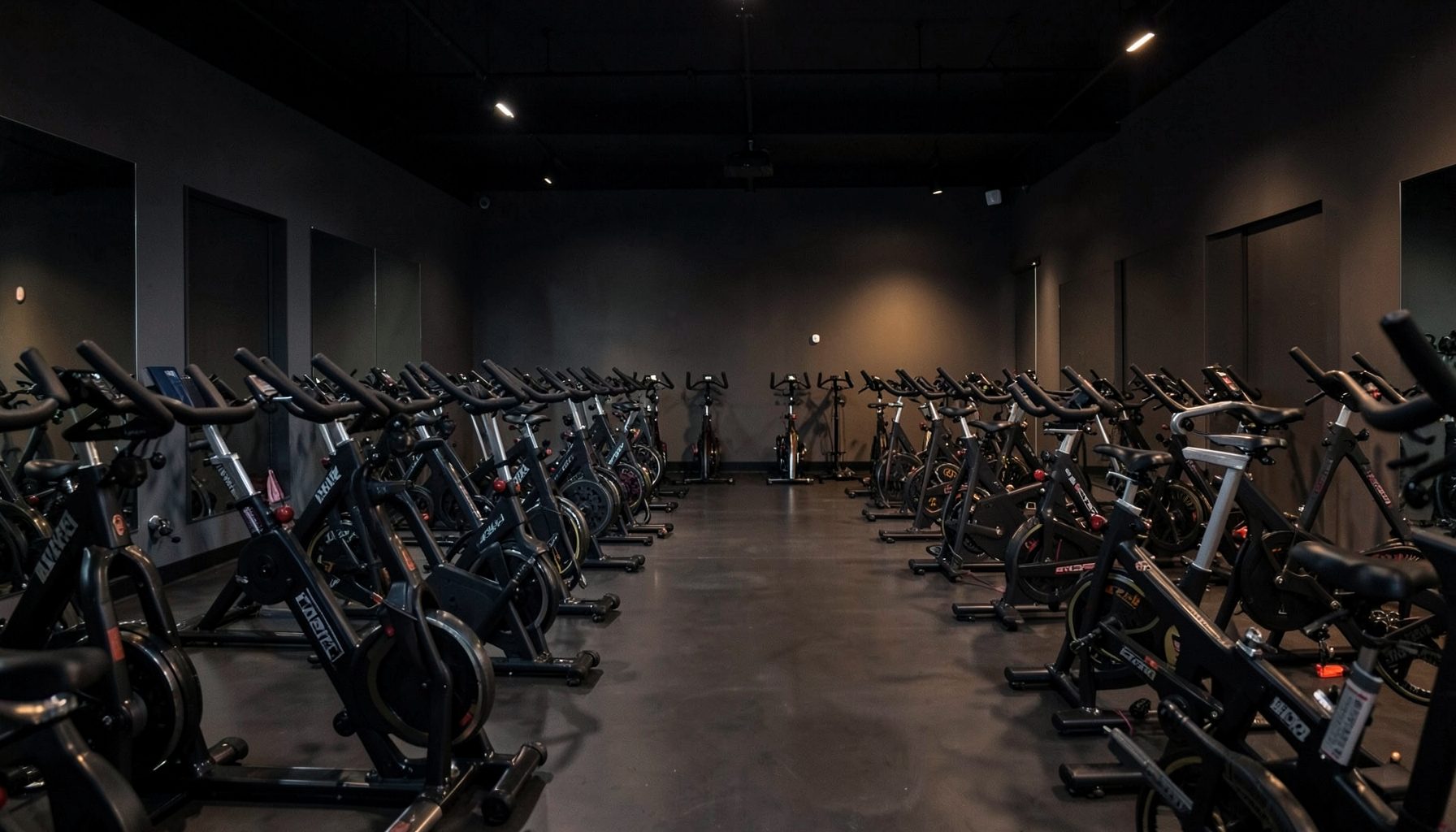 Group cycling studio with rows of stationary bikes, dim ambient lighting, and dark-toned interior